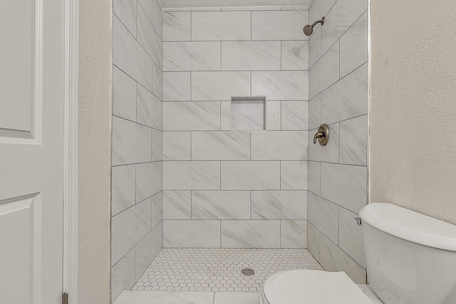 bathroom with a shower stall, toilet, and a textured wall