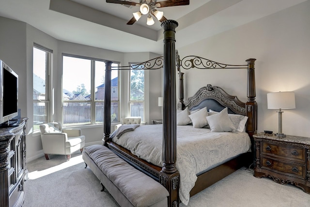 bedroom featuring baseboards, a water view, ceiling fan, light colored carpet, and a raised ceiling