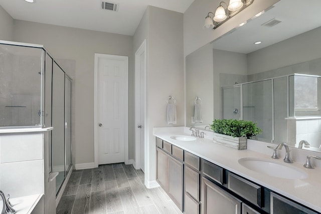 bathroom with a sink, visible vents, wood finish floors, and a stall shower