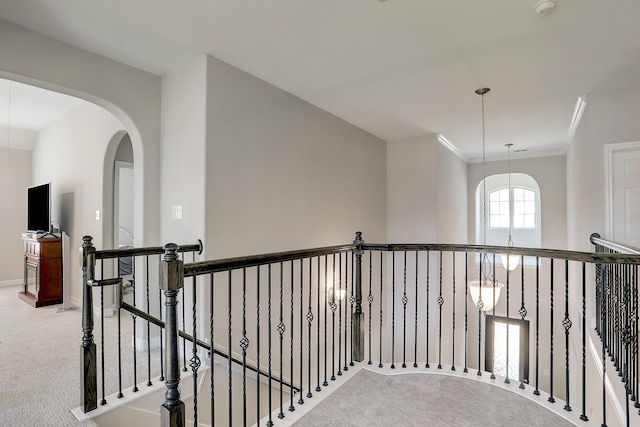 corridor featuring an upstairs landing, carpet floors, arched walkways, crown molding, and baseboards