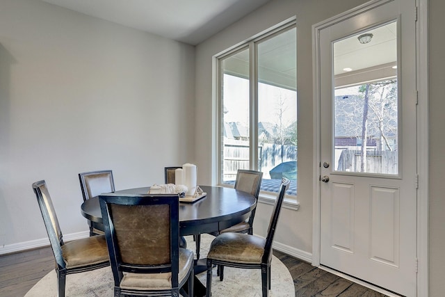 dining room with dark wood finished floors, a healthy amount of sunlight, and baseboards