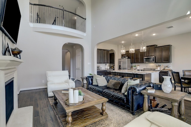 living room with visible vents, baseboards, dark wood finished floors, recessed lighting, and arched walkways