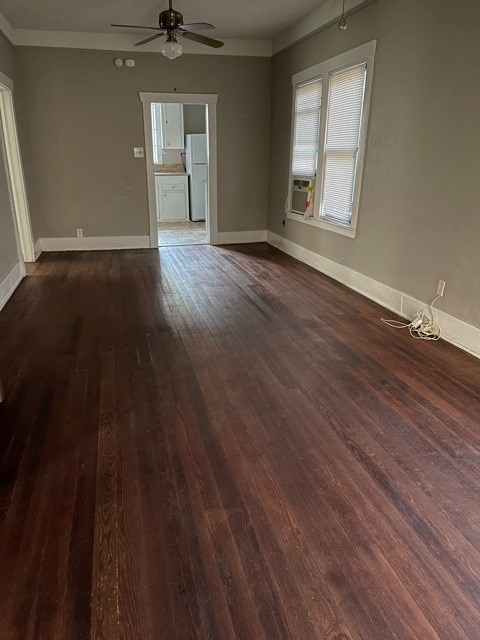 empty room with hardwood / wood-style flooring, ornamental molding, baseboards, and ceiling fan