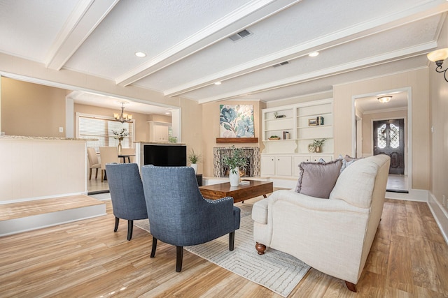 living room featuring wood finished floors, visible vents, beam ceiling, and a chandelier