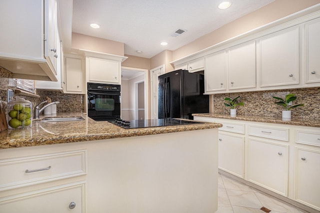 kitchen with visible vents, a peninsula, stone countertops, a sink, and black appliances