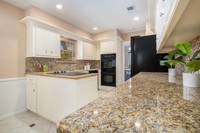 kitchen with black appliances, white cabinets, a peninsula, and backsplash