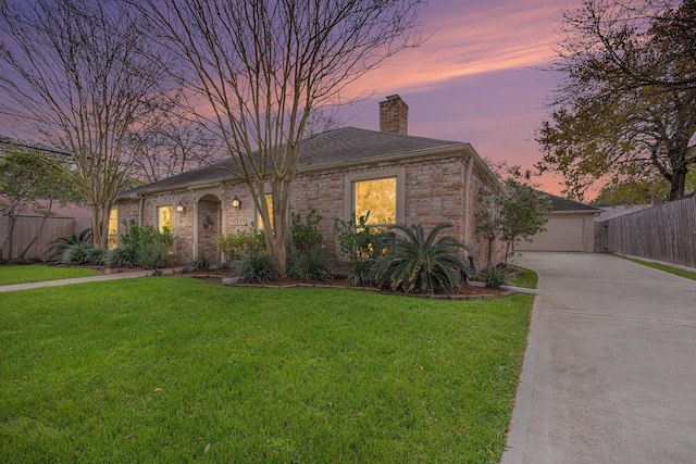 view of front facade with a chimney, a lawn, concrete driveway, and fence