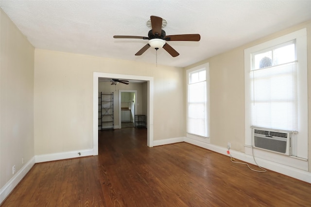 empty room featuring cooling unit, a ceiling fan, wood finished floors, baseboards, and a textured ceiling