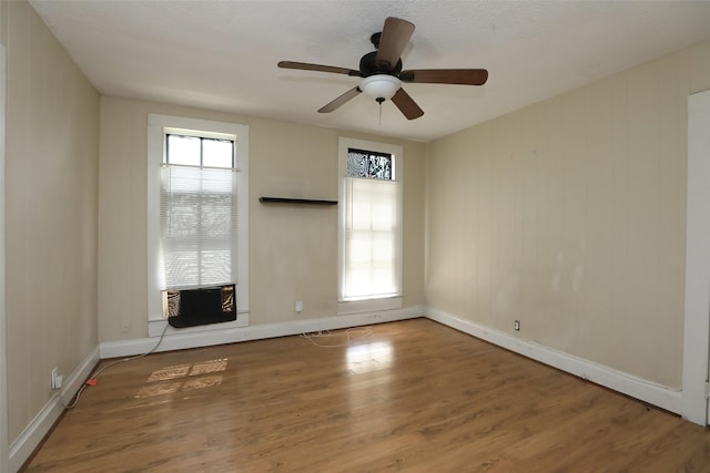 unfurnished room with a wealth of natural light, baseboards, wood finished floors, and ceiling fan