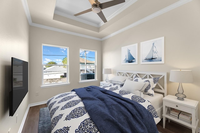 bedroom with crown molding, baseboards, wood finished floors, a raised ceiling, and a ceiling fan