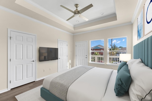 bedroom with ornamental molding, a raised ceiling, and dark wood-style flooring