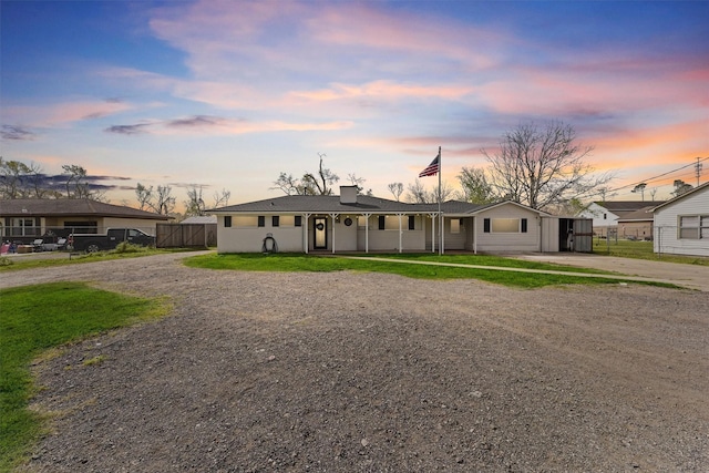 view of front of property with a chimney, dirt driveway, and fence