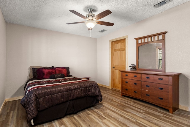 bedroom with visible vents, light wood-style floors, and a textured ceiling