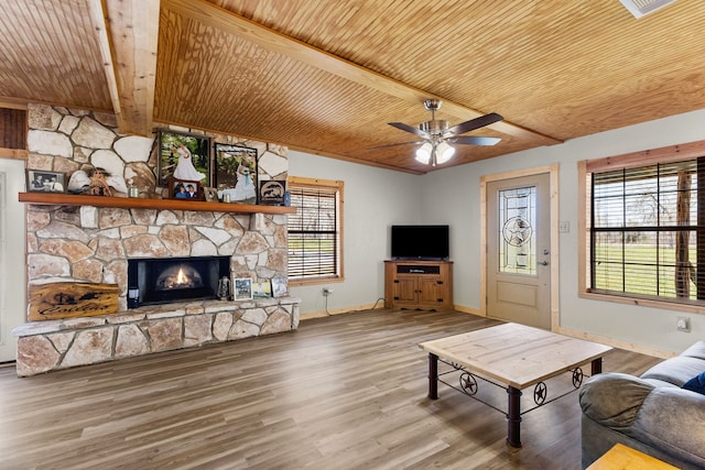 living area featuring beam ceiling, a fireplace, wood ceiling, and wood finished floors