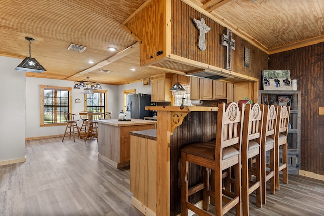 kitchen with light wood-style flooring, light brown cabinets, a kitchen island, stainless steel fridge with ice dispenser, and wood ceiling