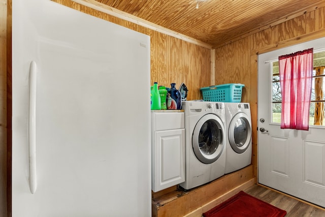 laundry area with wood walls, wooden ceiling, wood finished floors, cabinet space, and independent washer and dryer