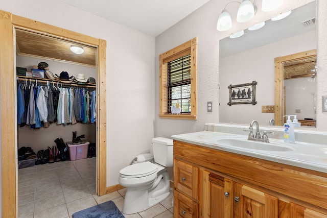 bathroom with tile patterned flooring, visible vents, a walk in closet, toilet, and vanity