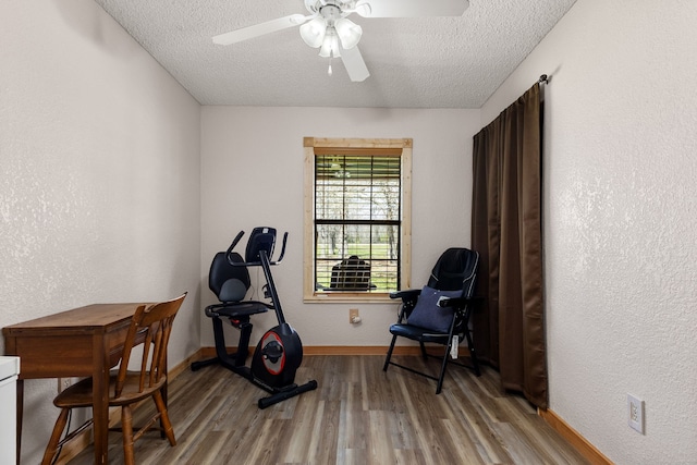 workout room featuring ceiling fan, baseboards, a textured ceiling, and wood finished floors