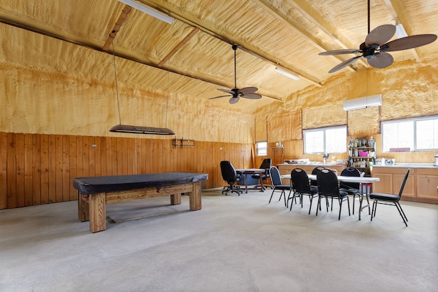 interior space featuring wood walls, high vaulted ceiling, concrete floors, and ceiling fan