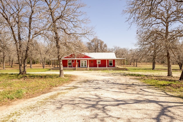 view of front of home with covered porch, driveway, and metal roof