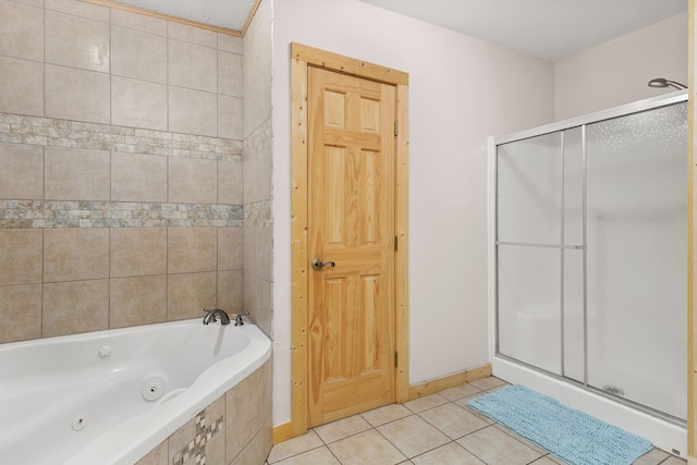 bathroom featuring tile patterned flooring, baseboards, a stall shower, and a whirlpool tub