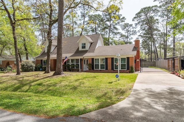 cape cod house featuring brick siding, a front lawn, concrete driveway, roof with shingles, and a gate