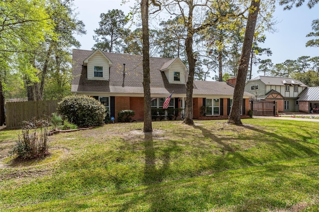 cape cod-style house with a front lawn, fence, brick siding, and roof with shingles