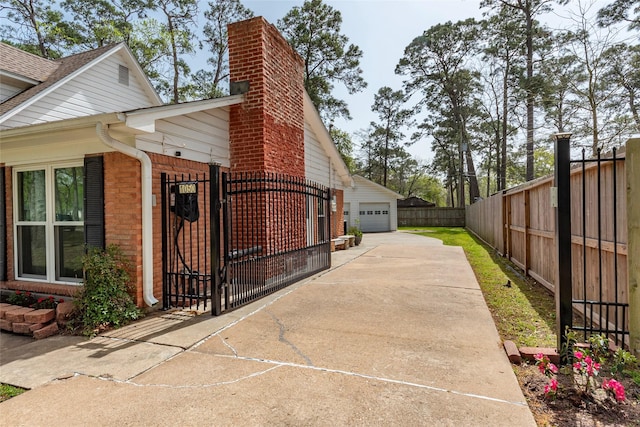 view of home's exterior featuring fence, a chimney, a garage, an outbuilding, and a gate