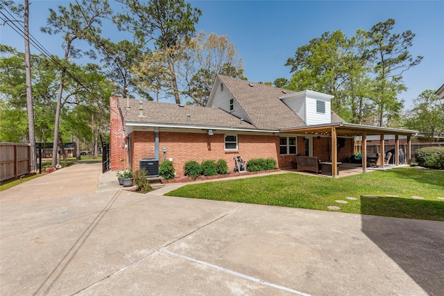 rear view of property with brick siding, fence, central AC unit, a lawn, and a patio area