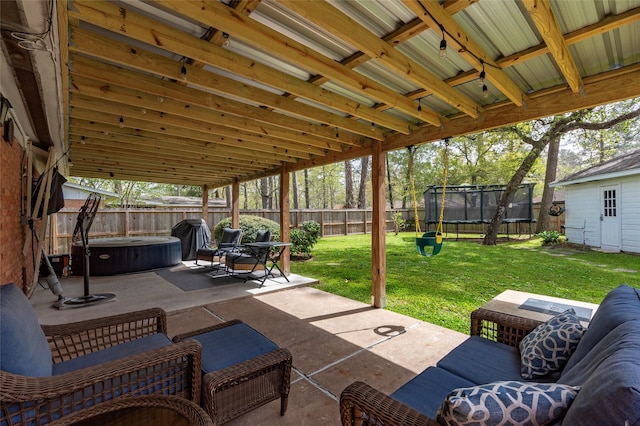 view of patio / terrace with a trampoline, a fenced backyard, and a hot tub