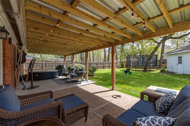 view of patio / terrace with a trampoline, a fenced backyard, and a hot tub