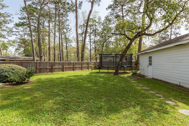 view of yard featuring a trampoline and fence