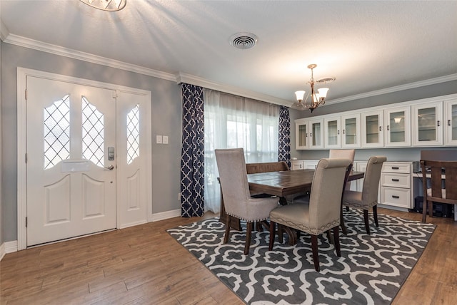 dining room featuring a notable chandelier, crown molding, visible vents, and wood finished floors