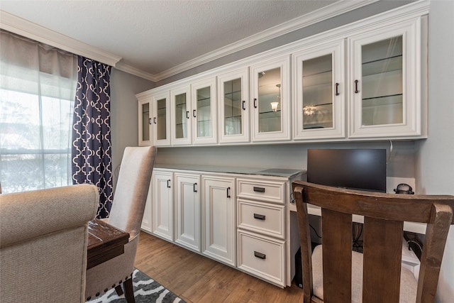 interior space with a textured ceiling, wood finished floors, and ornamental molding