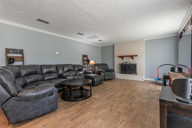 living area featuring visible vents, light wood-style flooring, a fireplace, and crown molding