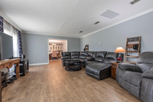 living area with a notable chandelier, light wood-style floors, visible vents, and ornamental molding