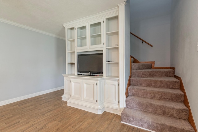 stairway featuring crown molding, baseboards, and wood finished floors