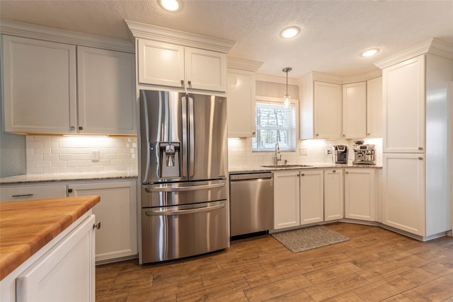 kitchen with white cabinets, wood finished floors, appliances with stainless steel finishes, and a sink