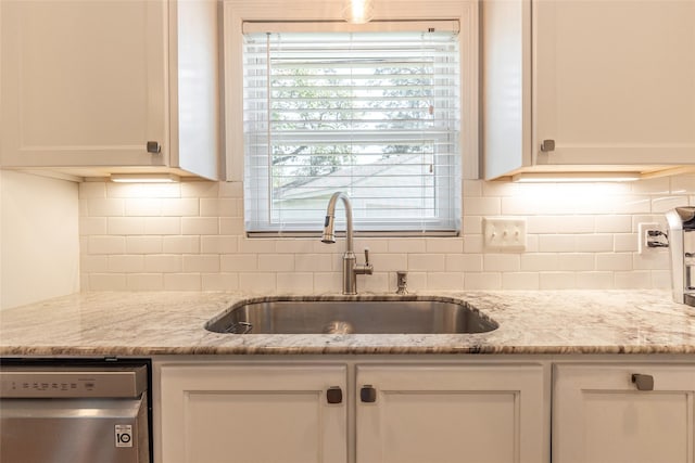 kitchen featuring stainless steel dishwasher, white cabinets, and a sink