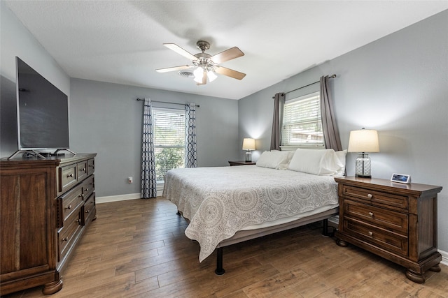 bedroom with multiple windows, baseboards, and wood finished floors