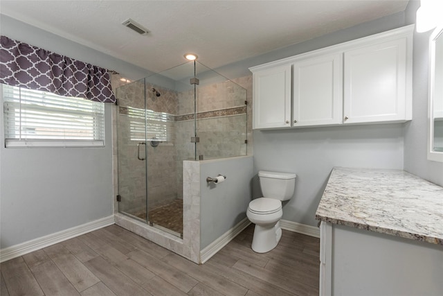 full bathroom featuring vanity, visible vents, wood finish floors, a stall shower, and toilet