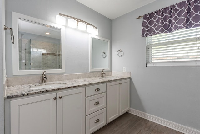 full bath with a tile shower, wood finished floors, baseboards, and a sink