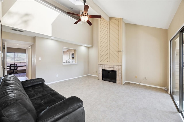 carpeted living area with visible vents, baseboards, a fireplace, high vaulted ceiling, and a ceiling fan