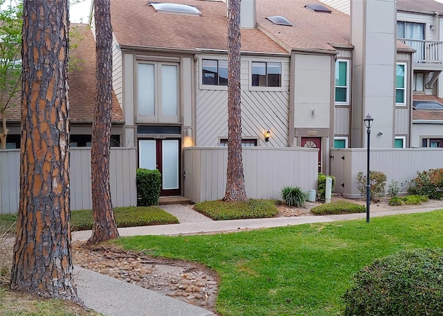 exterior space featuring fence, a lawn, and roof with shingles
