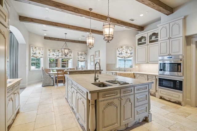 kitchen with stone tile flooring, visible vents, hanging light fixtures, and a sink