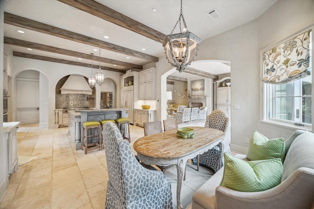 dining space with arched walkways, a chandelier, beam ceiling, and visible vents