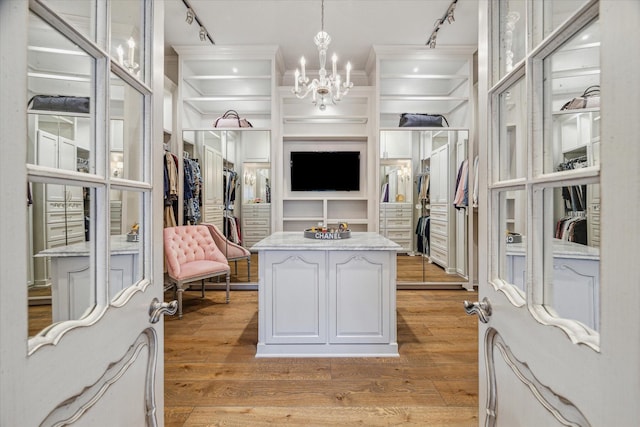 spacious closet with light wood-style floors and a chandelier