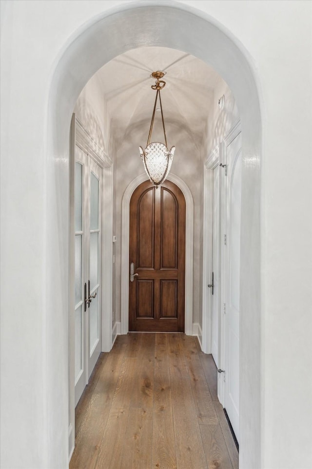 corridor with hardwood / wood-style flooring and arched walkways