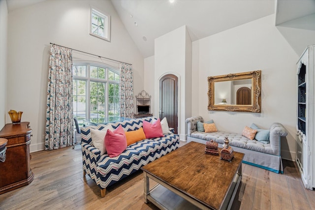 living room featuring hardwood / wood-style flooring, a healthy amount of sunlight, baseboards, and high vaulted ceiling