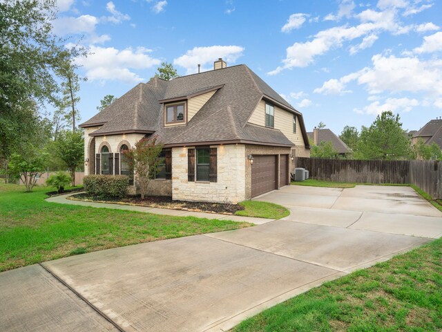 12530 Sharps Ln, Magnolia, TX 77354 - view of side of home with stone siding, roof with shingles, concrete driveway, an attached garage, and a chimney